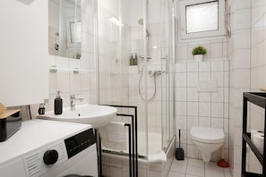A modern bathroom with a glass-enclosed shower, a white sink, and a toilet. - Vrbo Property (Heidelberg)