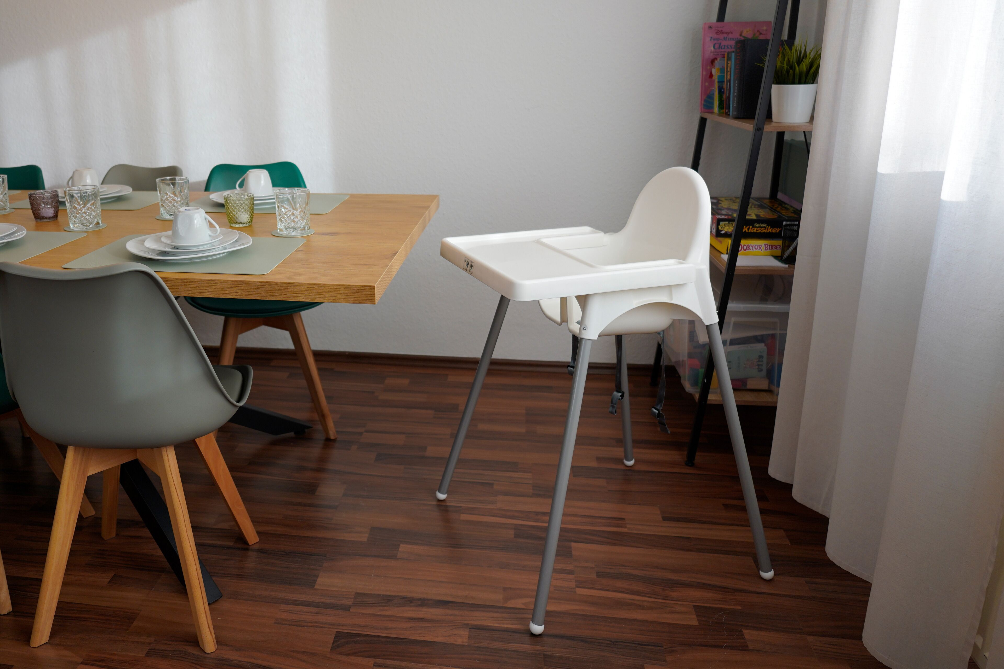 Ein Essbereich mit einem Holztisch, Stühlen und einem weißen Hochstuhl.