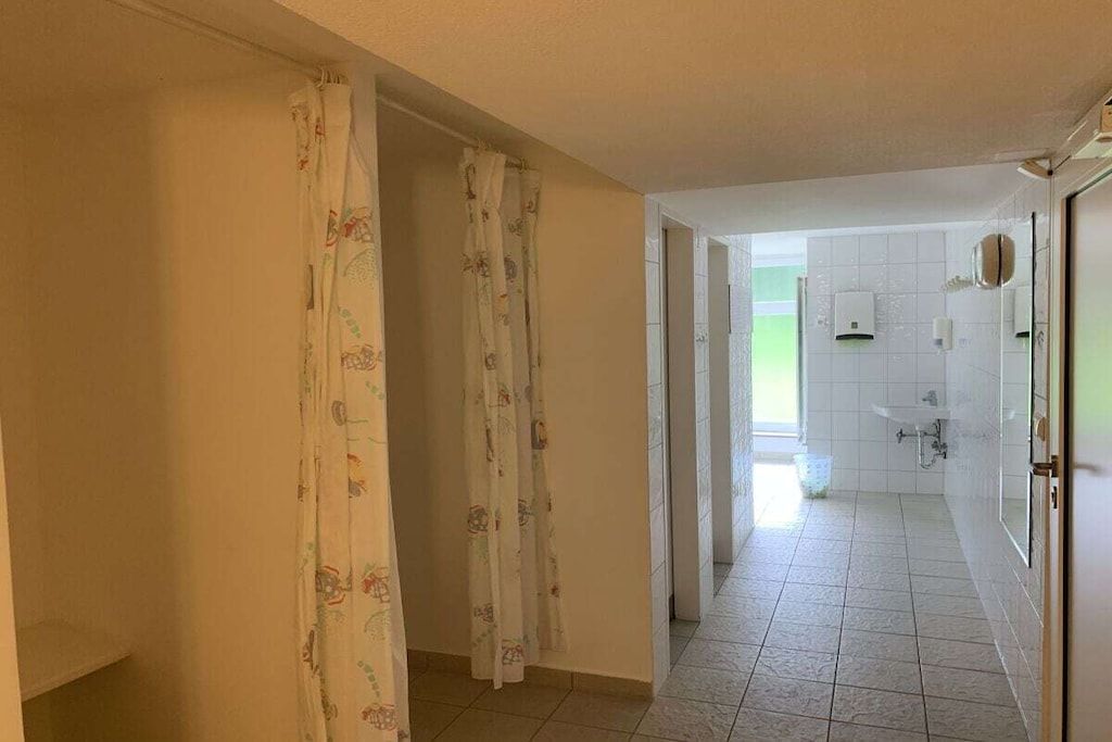A bathroom with white tiles, a sink, and a shower area.