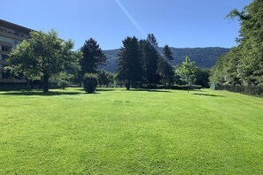 Ein gepflegter Rasen mit Bäumen und einem Berg im Hintergrund.