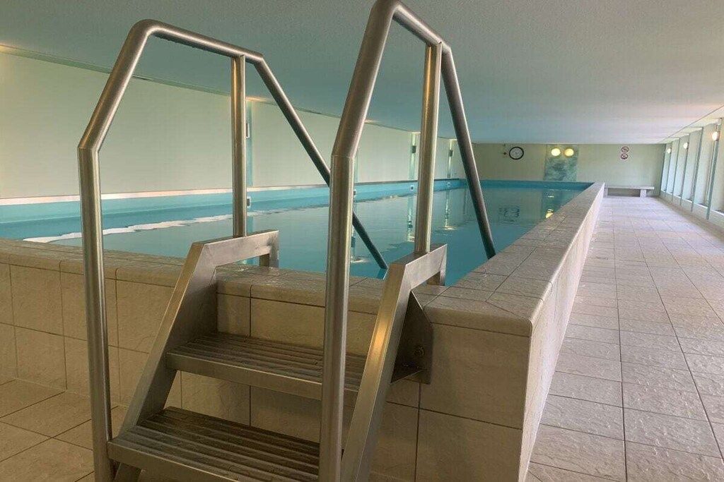 Piscina interna com escada de metal que dá acesso à água.