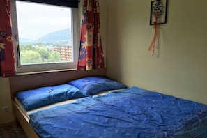 Une pièce avec un lit, une fenêtre avec des rideaux et un élément de décoration murale.