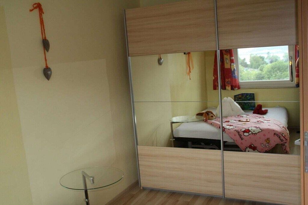 Een slaapkamer met een spiegelkast, een nachtkastje en een raam met gordijnen.