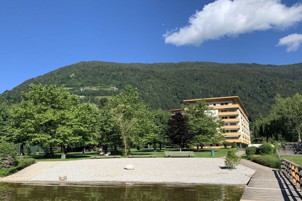 A hotel with a pool, surrounded by trees and a mountain backdrop.