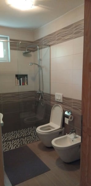 Un bagno con doccia, WC, bidet e porta asciugamani.