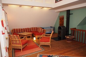 Ein gemütliches Wohnzimmer mit einer Couch, Sesseln, einem kleinen Tisch und einem Kamin.