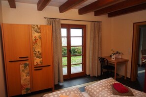 Ein Schlafzimmer mit einem Bett, einem Holzschrank, einem Schreibtisch und einem Fenster mit Vorhängen.