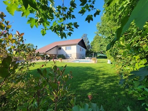 Ein Haus mit rotem Dach, Schwimmbecken und einem gepflegten Rasen.