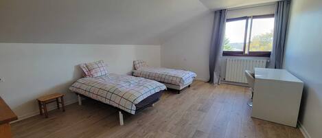 Una habitación con dos camas, una mesita y un radiador.