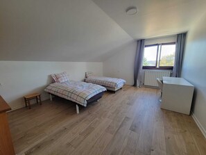 Ein Zimmer mit zwei Betten, einem kleinen Tisch und einer Heizung.