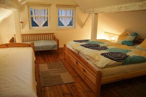 A bedroom with a wooden bed, a smaller bed, two windows with curtains, and a wooden ceiling. - Oriole at the forester's farm (Burg)