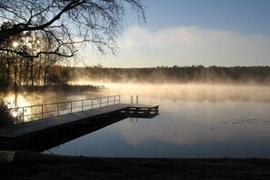 A calm lake with a dock extending into the water, surrounded by trees and a clear sky. - Holiday apartment with 1 bedroom (Neustrelitz OT Klein Trebbow)