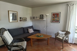 A living room with a sofa, two chairs, a coffee table, and wall art including a Picasso painting. - Holiday apartment with 1 bedroom (Neustrelitz OT Klein Trebbow)