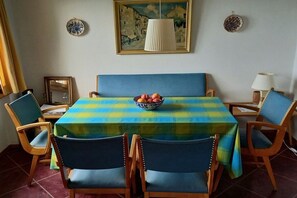 A dining area with a checkered tablecloth, wooden chairs, and a bowl of fruit. - Holiday home in Magadino with swimming pool (Magadino)