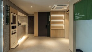 Rebedor d'hotel amb taulell de targetes d'auto-servei, taulell de recepció i zona de recepció.