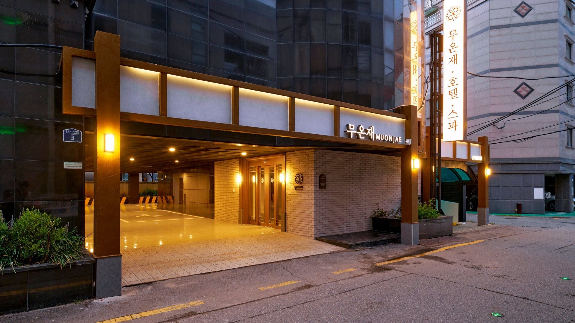 A hotel entrance with a modern design, featuring a brick facade and illuminated signage.