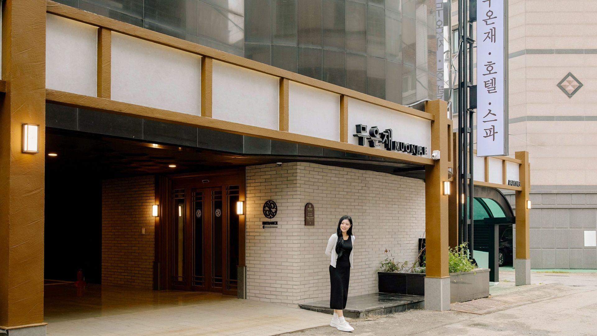 A hotel entrance with a sign reading 'MUONAE' and a parking sign.