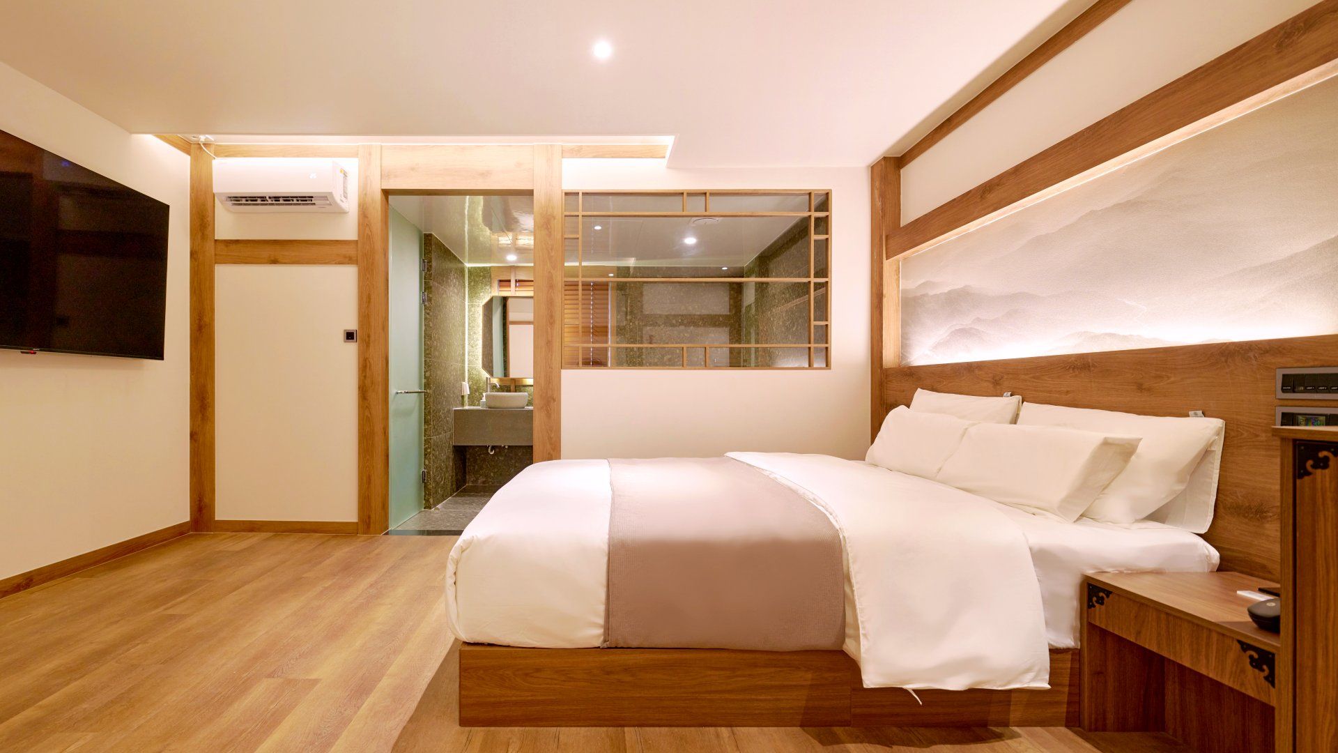 A modern bedroom with a large bed, wooden headboard, and a television mounted on the wall.