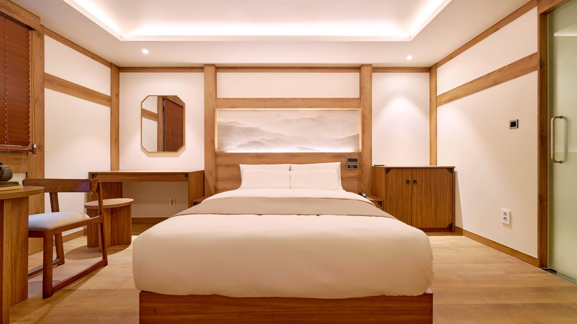 A bedroom with a large bed, wooden furniture, a desk, and a cabinet.
