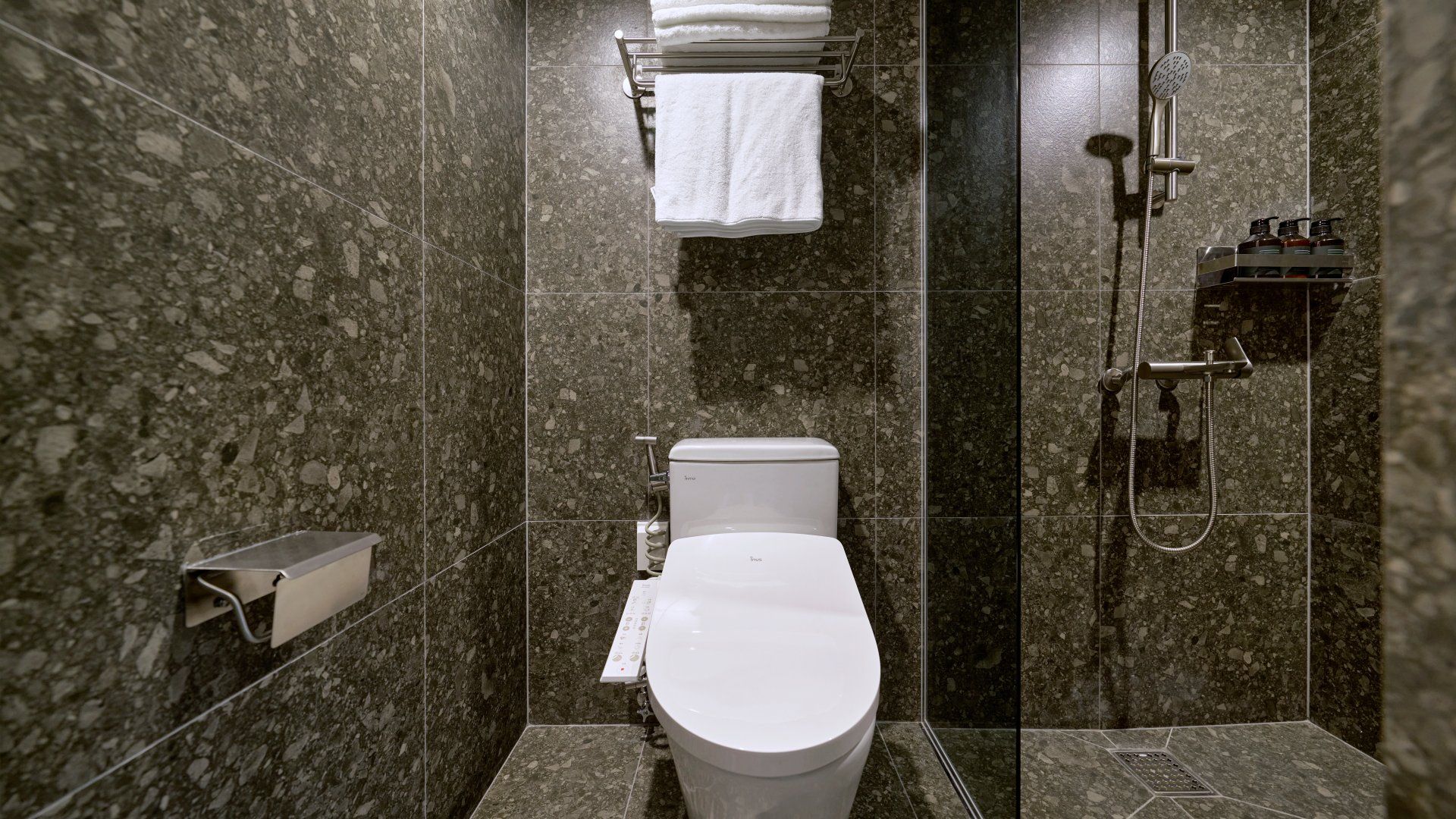 A modern bathroom with a toilet, a towel rack, and a shower.