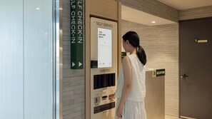 Un taulell d'auto-servei amb instruccions en diversos idiomes, una zona de recepció i un senyalitzador de personal autoritzat.