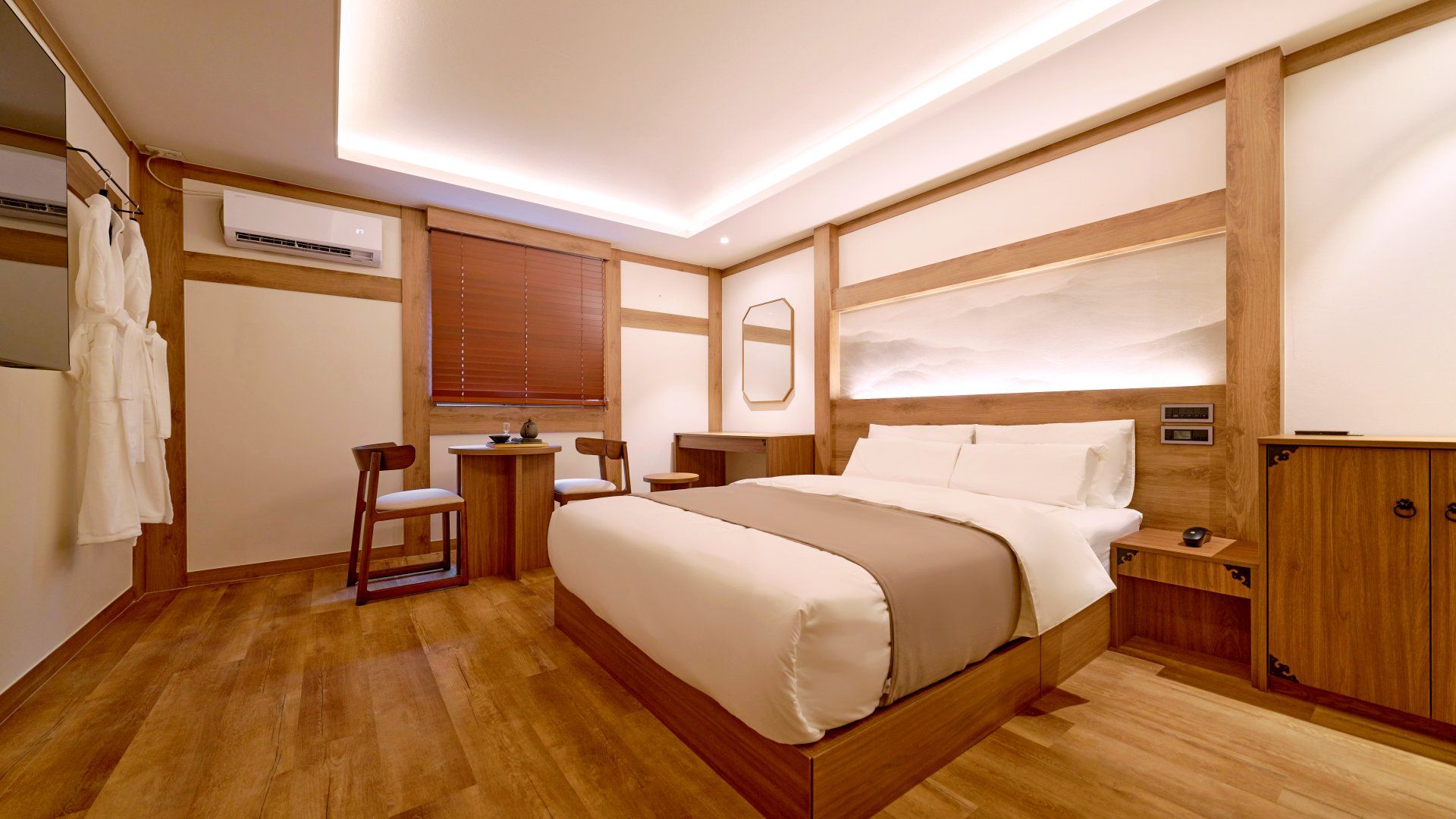 Ein Hotelzimmer mit einem großen Bett, Holzmöbeln, einem kleinen Tisch, Stühlen, einer Klimaanlage und einem Kleiderschrank.