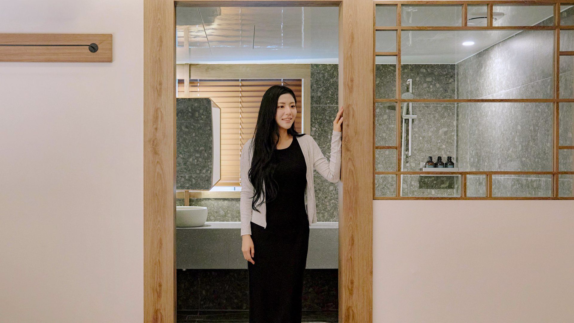 A person standing in a doorway with a modern bathroom visible through the door.