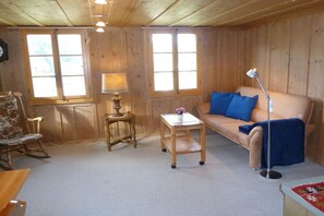 A cozy room with a sofa, a rocking chair, a small table with a lamp, and a floor lamp. - South-facing slope of Rüschegg (Rüschegg-Heubach)