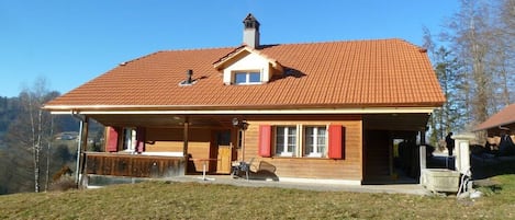 A two-story house with a red-tiled roof, a small attached garage, and a covered porch area.
