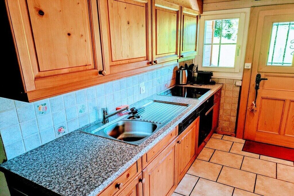 A kitchen with wooden cabinets, a granite countertop, a stainless steel sink, and a window.
