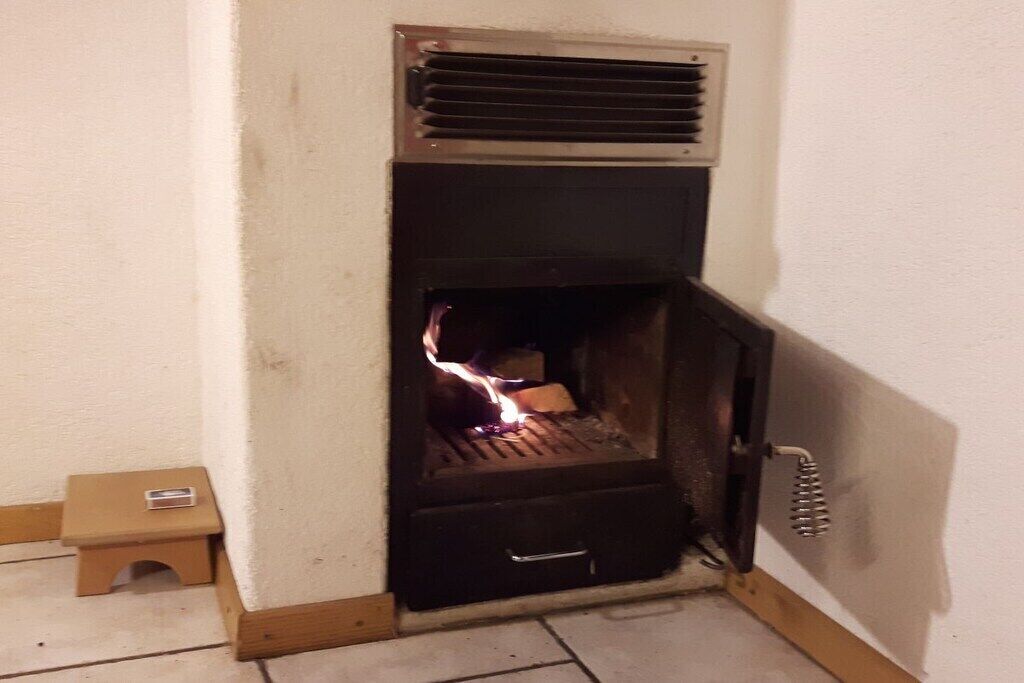 Una habitación de esquina con chimenea, un taburete pequeño y un radiador.