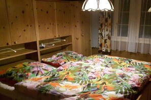 A room with a bed, wooden wardrobe, and a window with curtains. - South-facing slope of Rüschegg (Rüschegg-Heubach)