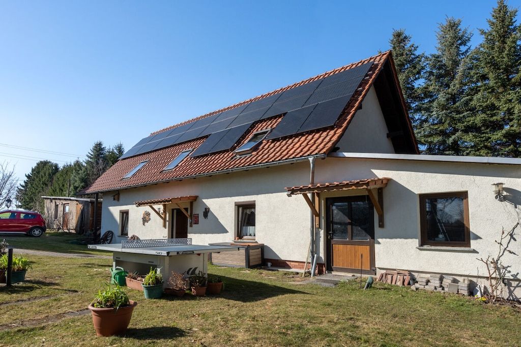 A house with a sloped roof, solar panels, a front porch, and a garage.