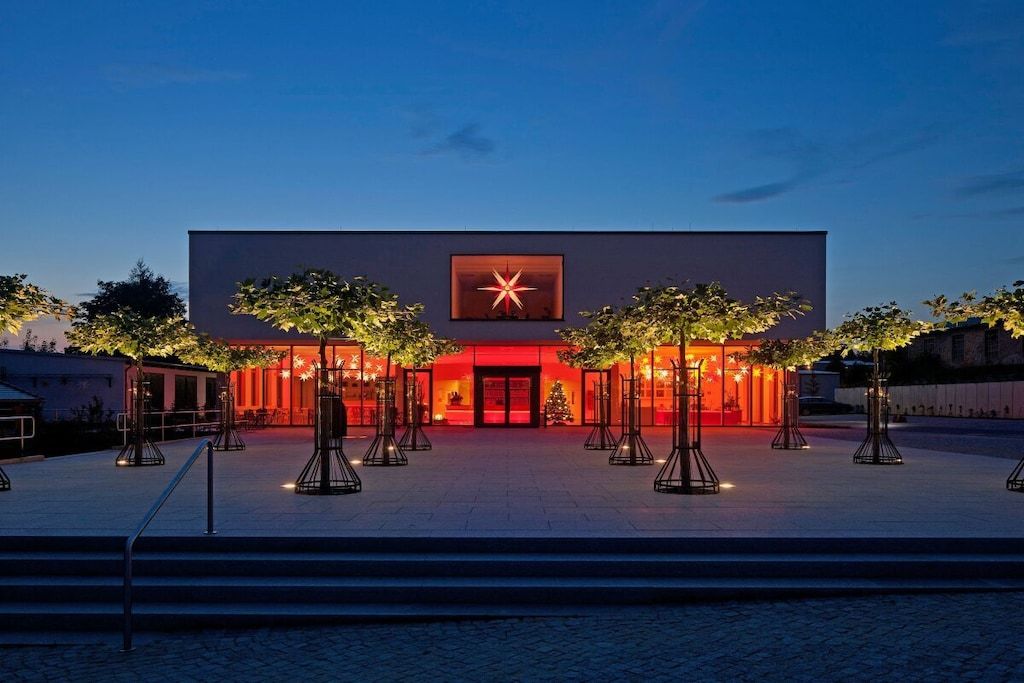 A modern building with a star-shaped logo, surrounded by trees and a paved area.