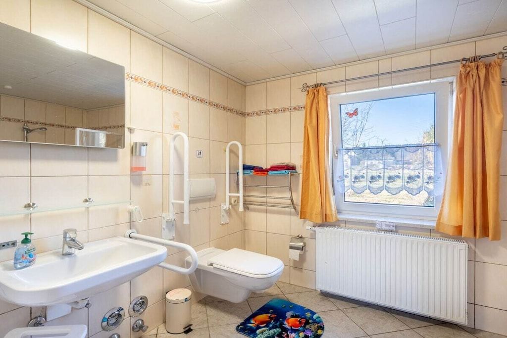 Bany amb vàter, rentapel i finestra amb cortines.