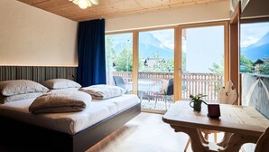 Un dormitorio con cama, una mesa y vistas a montañas a través de amplios ventanales.