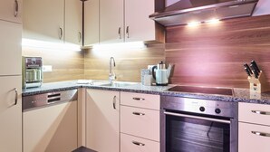Una cocina moderna con horno empotrado, cafetera y hervidor.