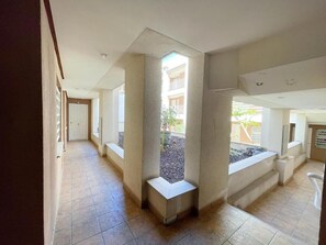 Un pasillo con piso de baldosas, un banco y una puerta al final.