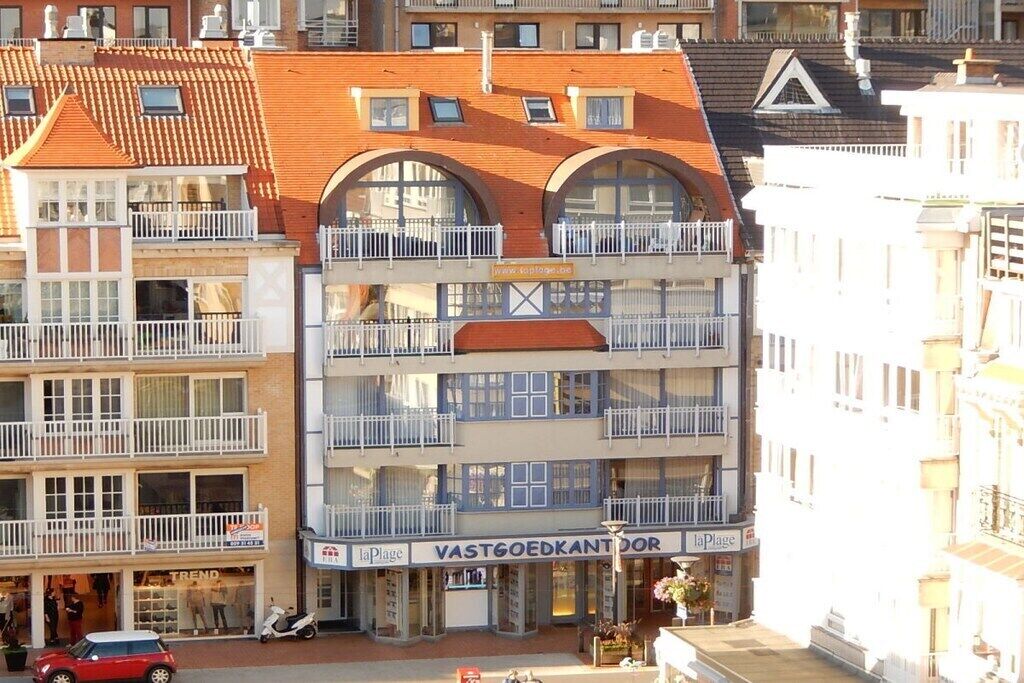 A multi-story building with balconies and a storefront labeled 'VASTGOEDKANTOR'.