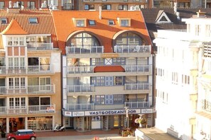 A multi-story building with balconies and a storefront labeled 'VASTGOEDKANTOR'. - Holiday home with 2 bedrooms (Westende-Dorp)