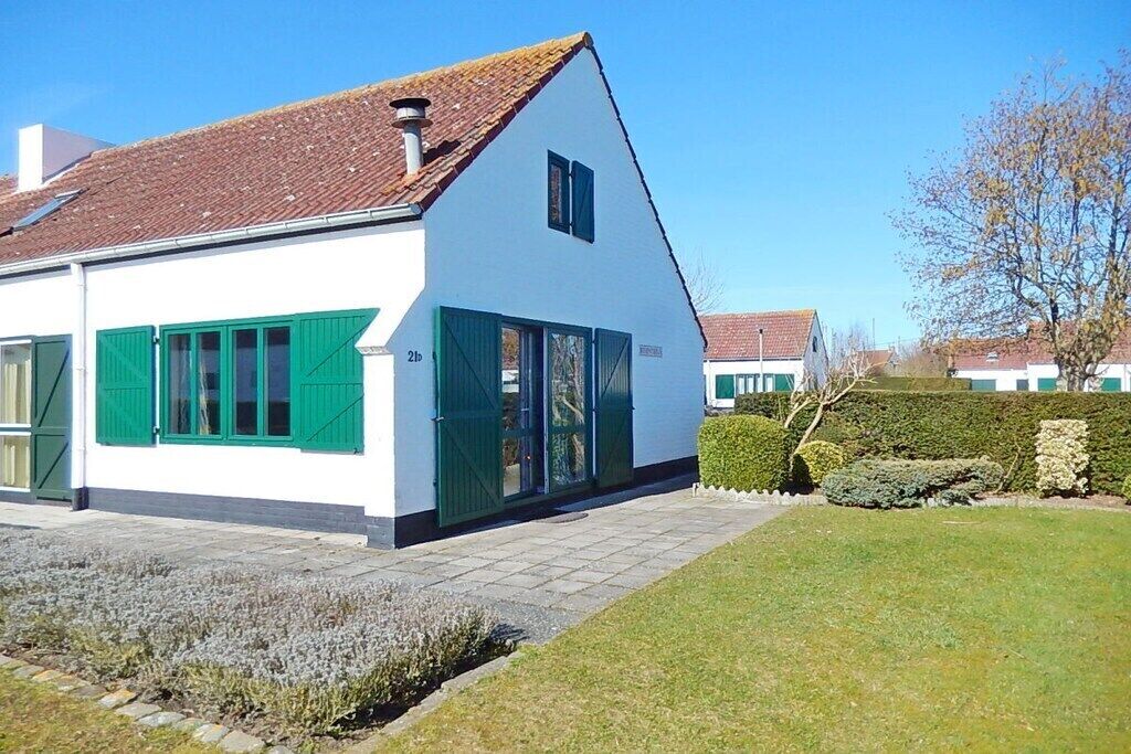 Un bâtiment blanc avec des volets verts et un toit recouvert de tuiles.