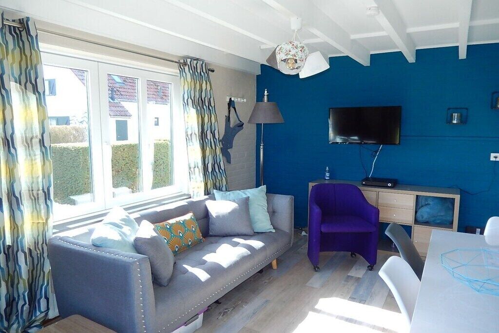 Une pièce comprenant un canapé, un fauteuil violet, un bureau et un téléviseur.