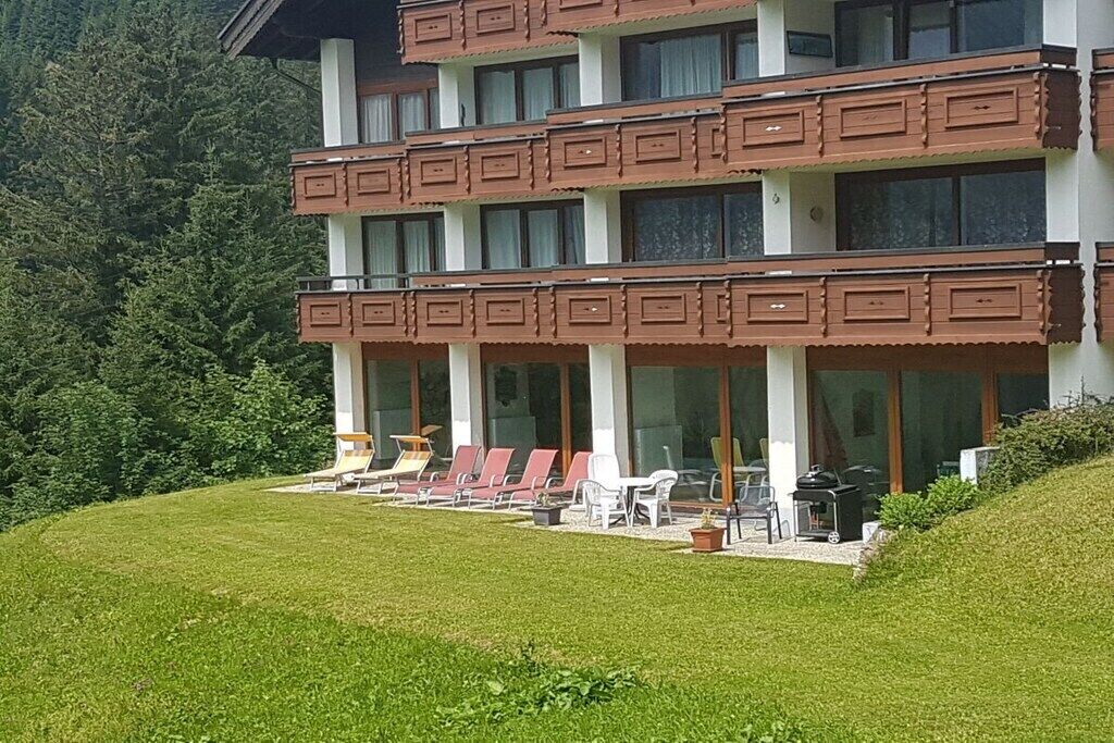 Ein mehrstöckiges Gebäude mit Balkonen, Sitzgelegenheiten im Freien und einer Rasenfläche.