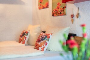 A bed with floral-patterned pillows, a white wall, and two paintings with floral designs. - Top 7 for 2 people / Ground floor (Schröcken)
