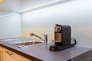 Une cuisine équipée d’un évier moderne, d’une machine à café et d’un plan de travail.