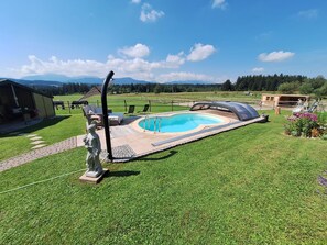 A swimming pool with a sunshade, a statue, and a view of mountains. - Wirtsstubn Vacation Rental, 75 m², Rooftop Terrace, Pool & Hot Tub (Siegsdorf)