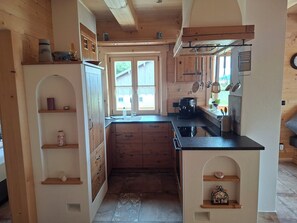 A kitchen with wooden cabinets, a coffee machine, and a window with a view. - Wirtsstubn Vacation Rental, 75 m², Rooftop Terrace, Pool & Hot Tub (Siegsdorf)