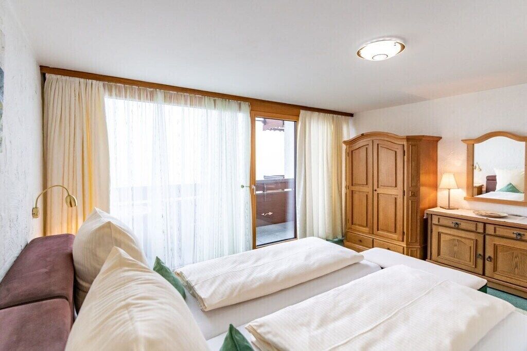 Ein Hotelzimmer mit einem Bett, einer Couch, einem Kleiderschrank und einer Glastür zu einem Außenbereich.