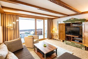 A living room with a sofa, a coffee table, a television, and a cabinet with shelves. - Top 16 for 2-6 people / 2nd floor (Schröcken)