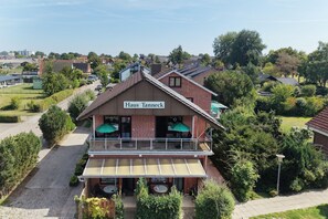 A two-story building with a sign reading 'Haus Tanneck.' It features a balcony with outdoor seating and a covered patio area. - Vrbo Property (Kellenhusen)